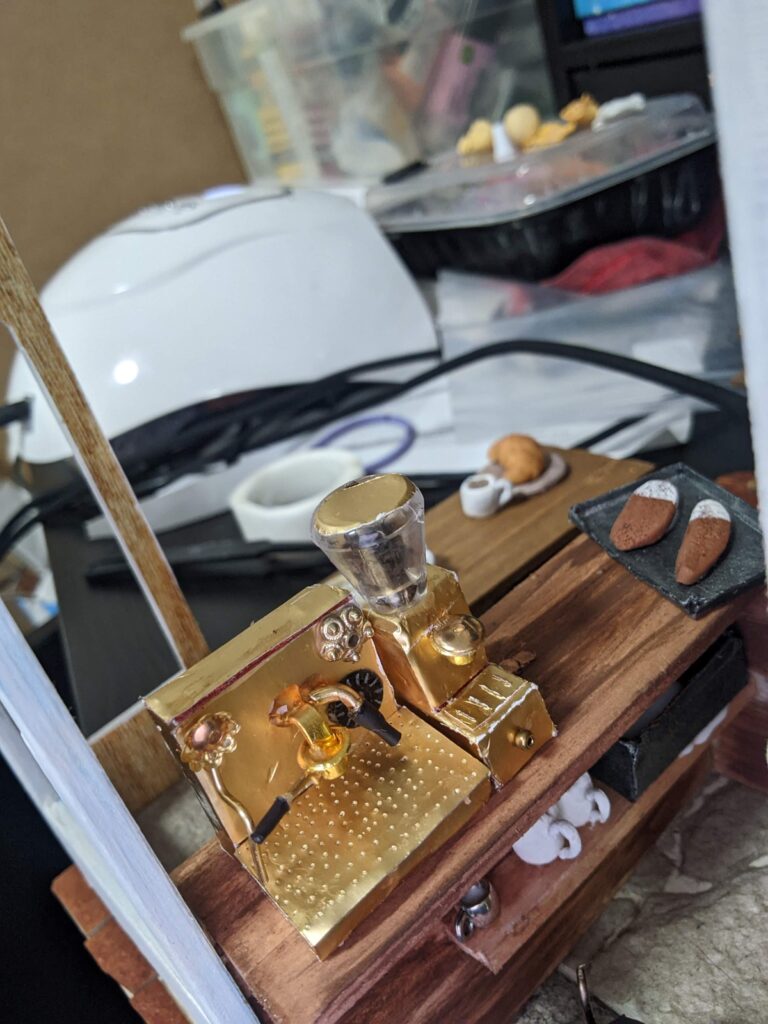 A view behind the counter of the coffee machine and grinder. In the books, they are not Gold coloured. Oops.