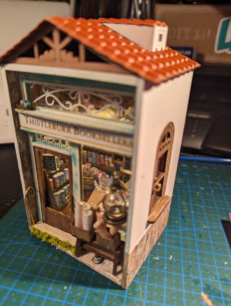 Thistleburr's booksellers from Travis Baldree's second novel, Bookshops and Bonedust. The focus is on the front view, the wood weather beaten and ocean wind blanched.