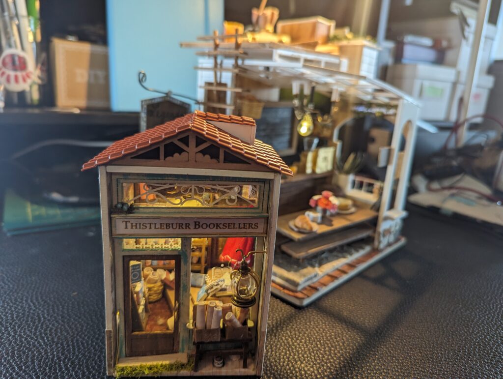 Thitsleburr Booksellers is in the foreground, at a 1:16 scale; in the background, we see Legends and Lattés as it was towards the climax of the novel.